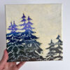 Hand holding canvas painting of pine trees with yellow skies